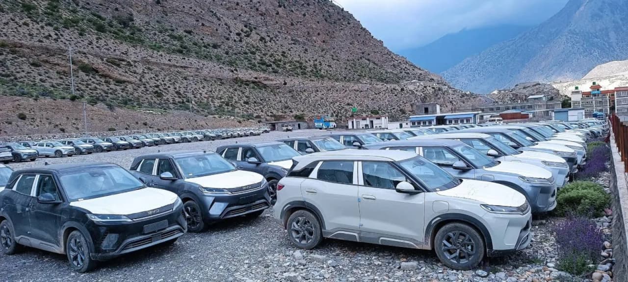 A parking area filled with various electric vehicles, some covered with protective wraps.