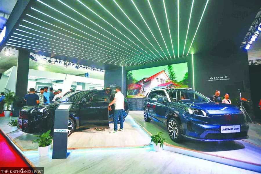 Two AION electric vehicles displayed at an auto show with attendees interacting.