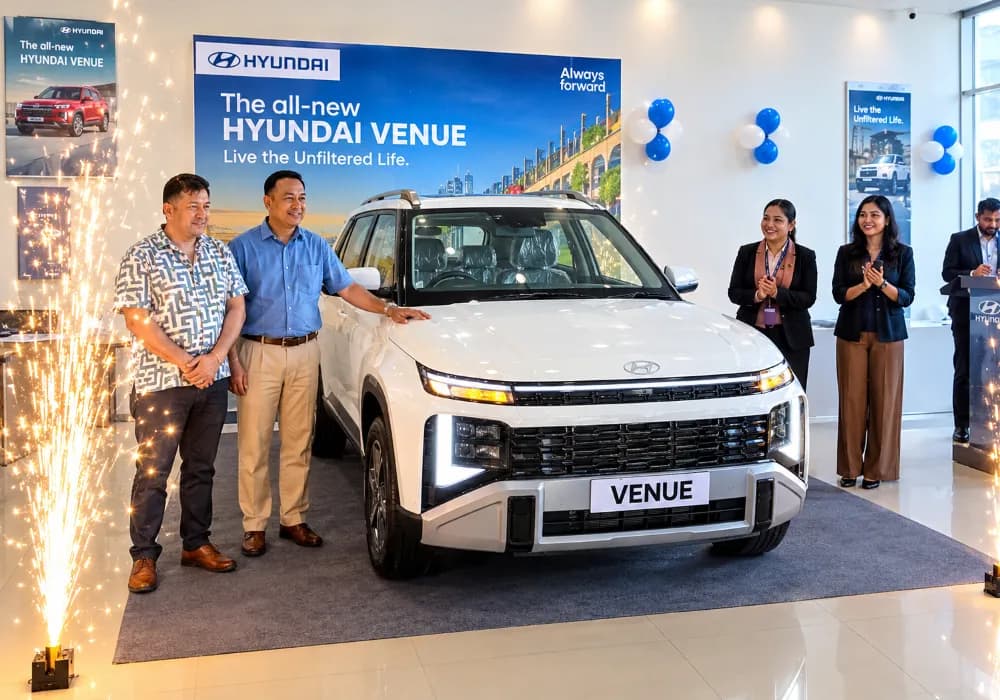 A white Hyundai Venue displayed in a showroom with people celebrating its launch.