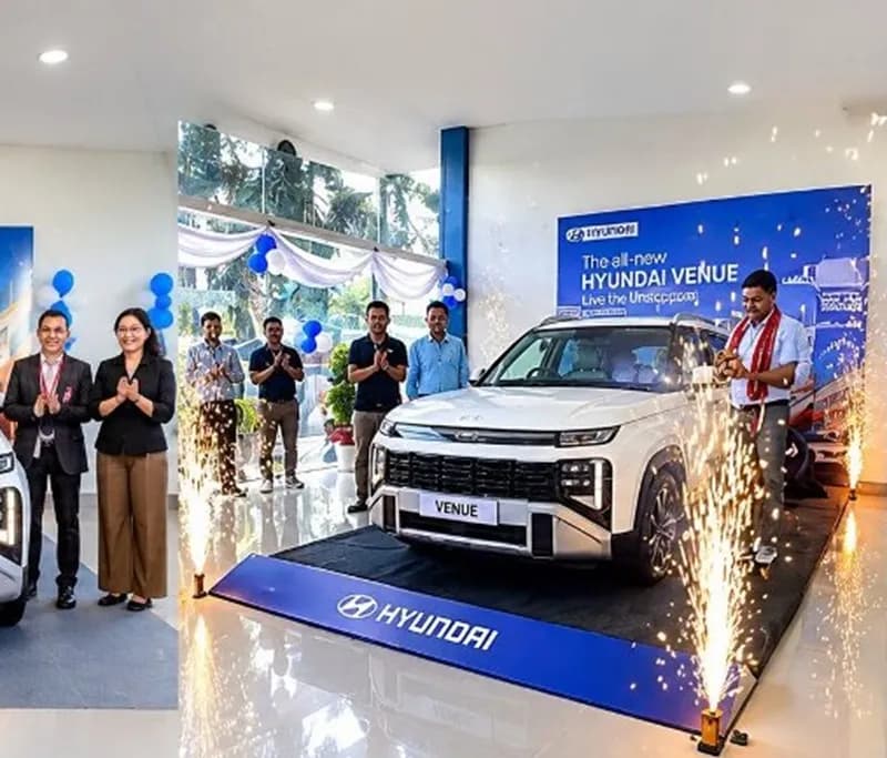 A white Hyundai Venue displayed at a showroom launch event with people celebrating.
