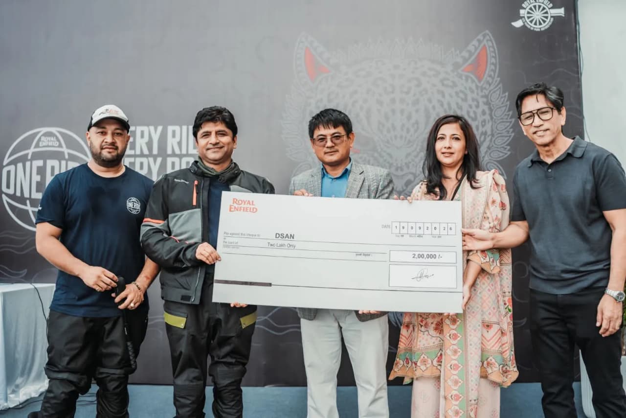 Group of individuals presenting a large cheque with 'Royal Enfield' branding.