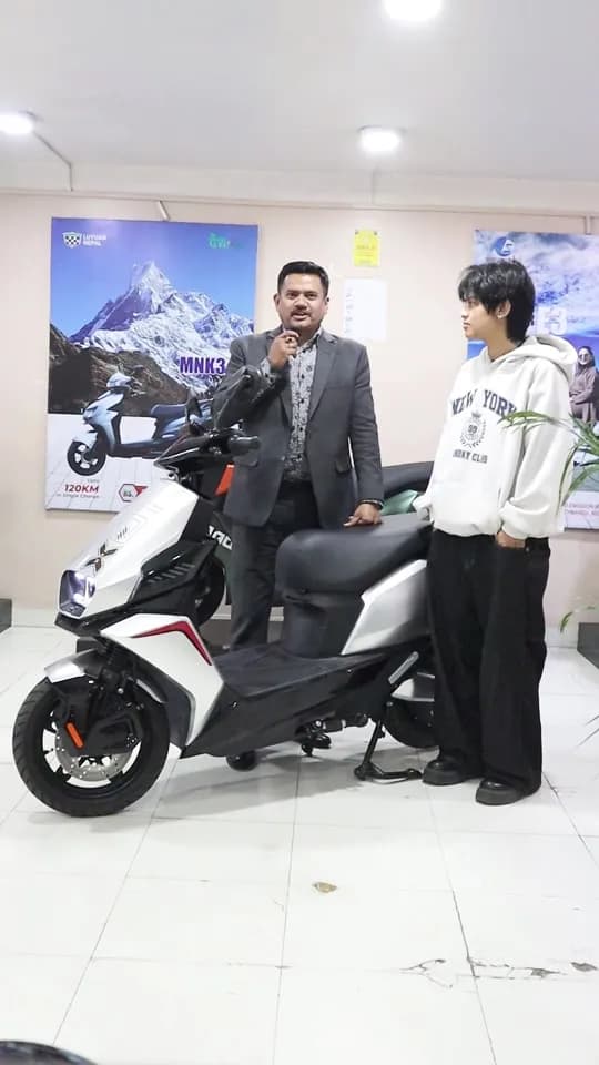 A Sarathi E-Scooter displayed in a showroom with two individuals, one speaking and the other listening.