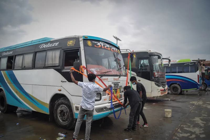 Workers decorating a bus with ribbons during Vishwakarma Puja.