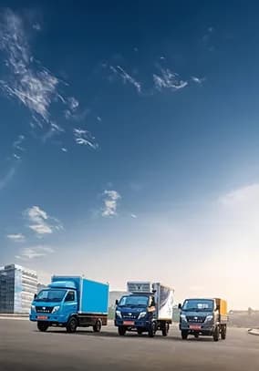 Three Volvo Eicher commercial vehicles parked in an open area under a clear sky.