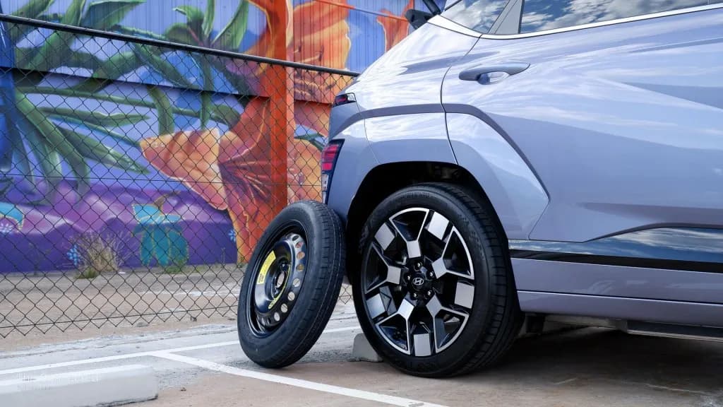 A vehicle with a spare tyre leaning against it, showcasing the contrast between traditional and modern vehicle designs.