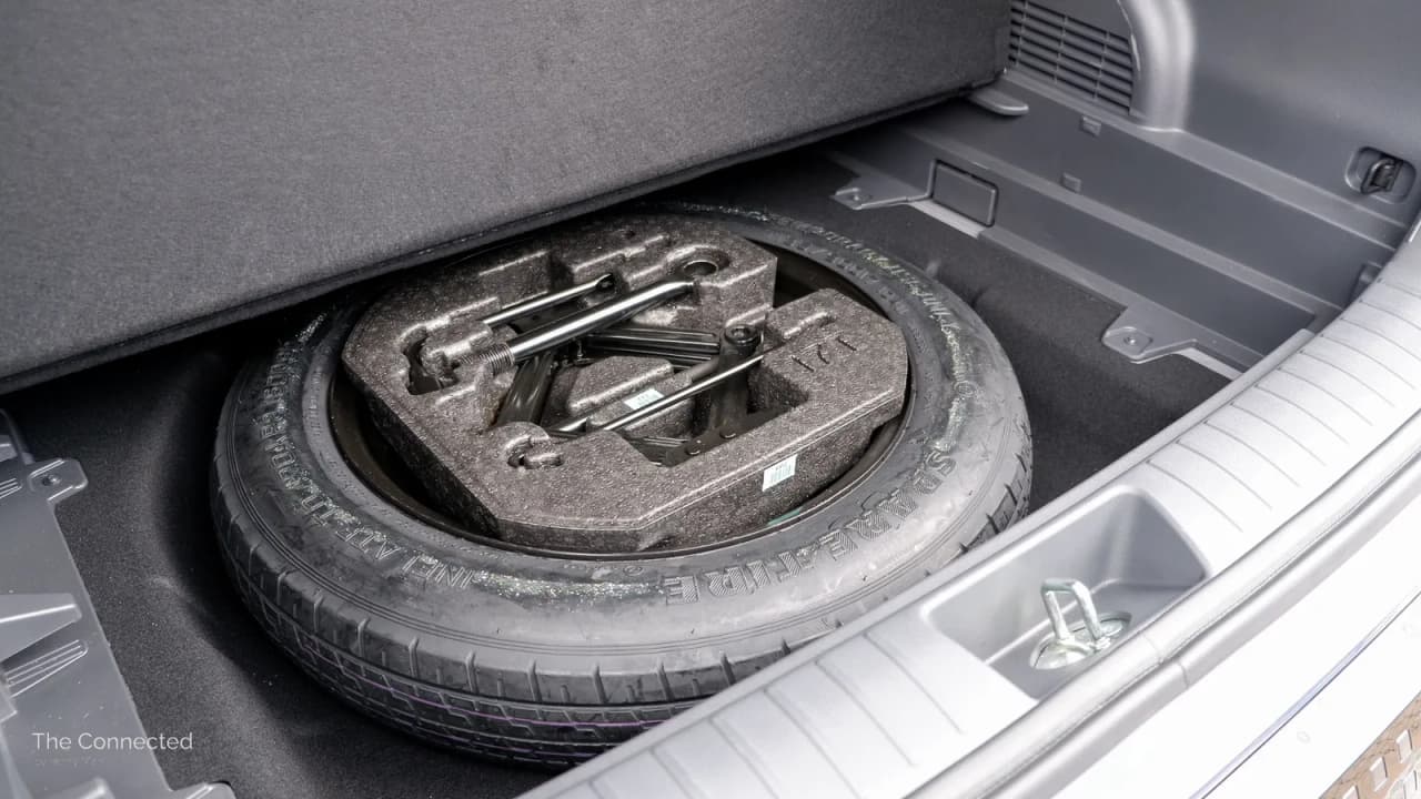 A spare tyre and tools stored in the boot of a vehicle.